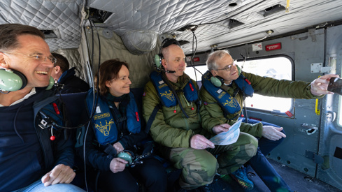 Fra innsiden av et Bell-helikopter i luften. Natos generalsekretær og statsministeren er ombord sammen med flere andre.