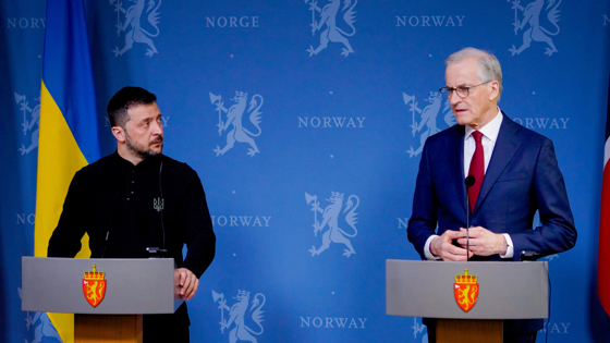 Zelenskyj and Støre at the press conference stage. Blue backdrop. National flags.